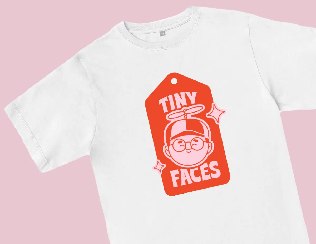 White t-shirt with red tag graphic featuring 'TINY FACES' text and stylized face icon.